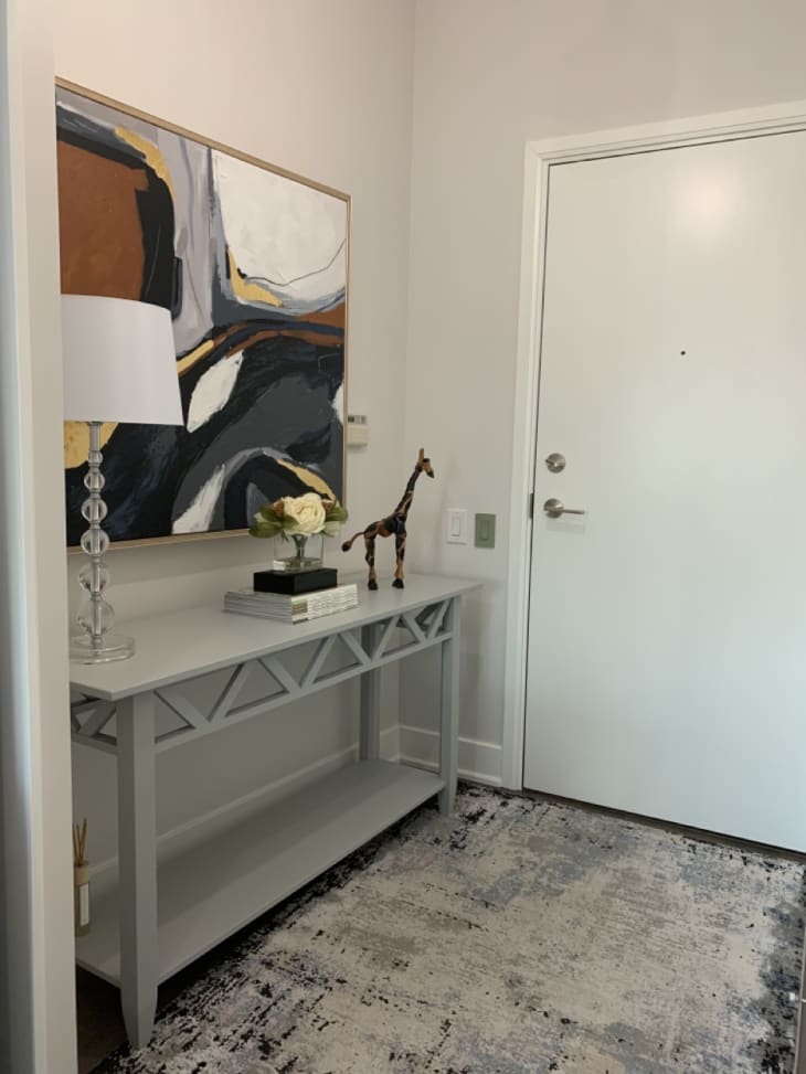 entryway with gray console table, art above, lamp and art objects