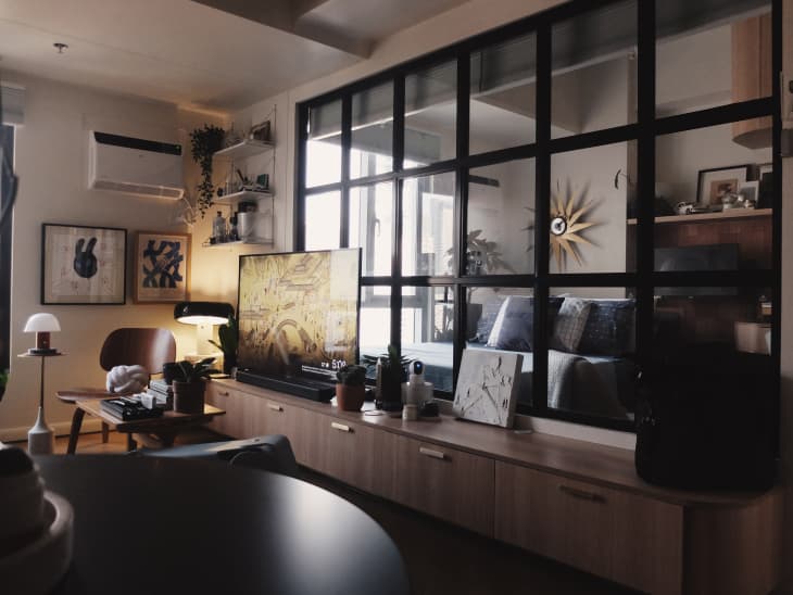 Multi-paned window separates living room from bedroom in studio apartment.