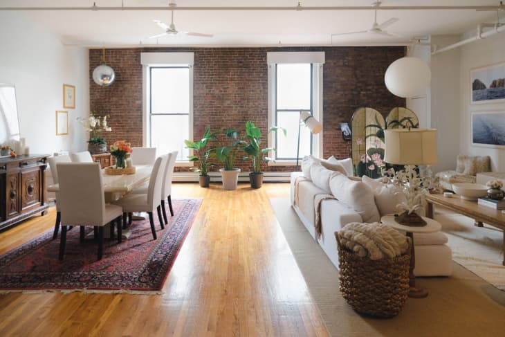 View of living room and dining room with exposed brick wall in background