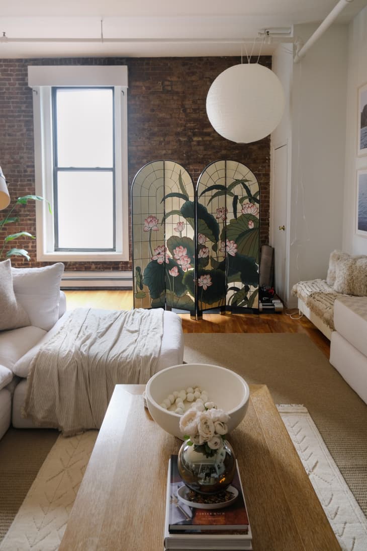 living room with white sofa, decorative divider screen, exposed brick wall