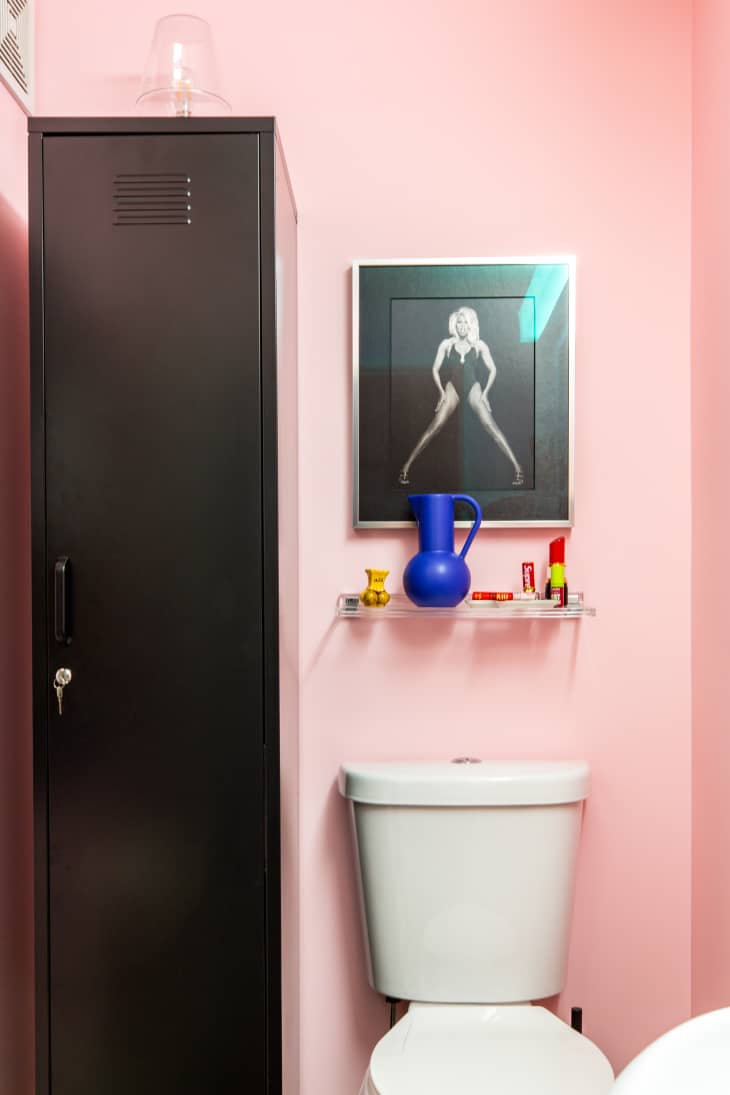 pink bathroom with red accents, framed posters