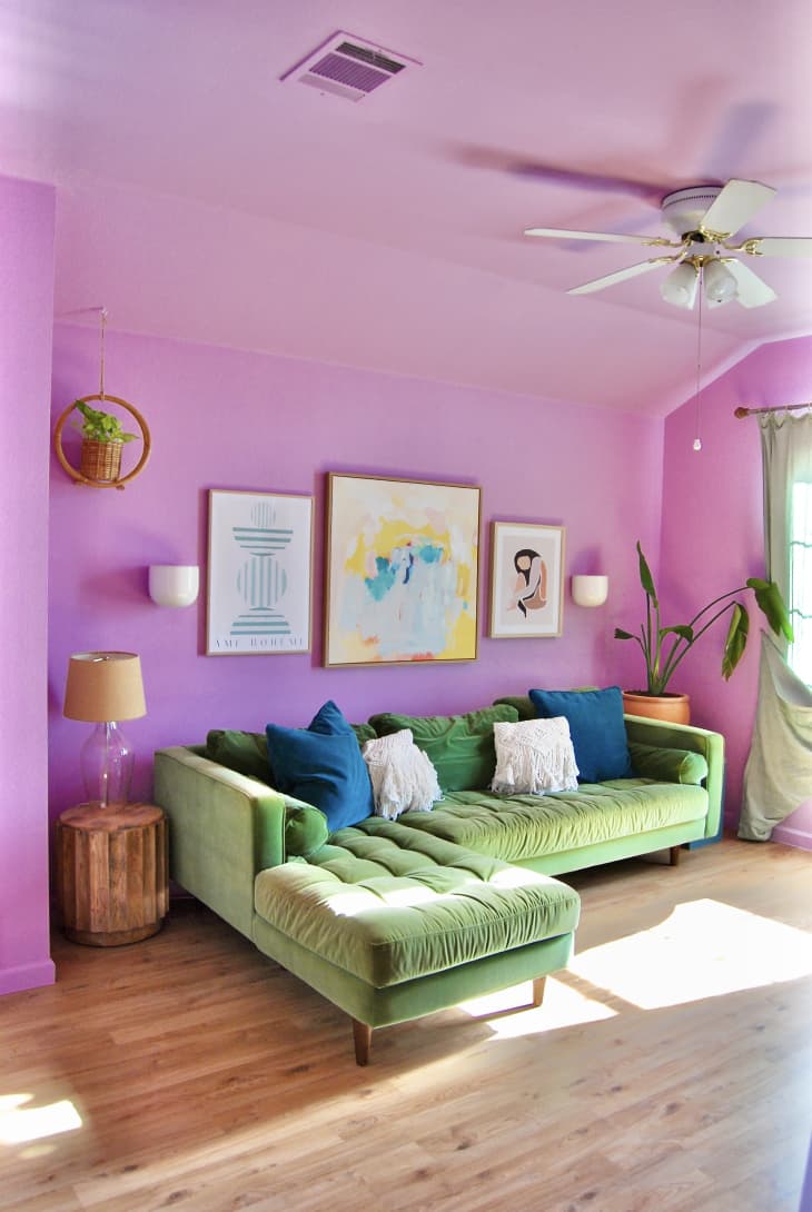 Prints mounted on wall above sage green sofa in brightly colored living room.
