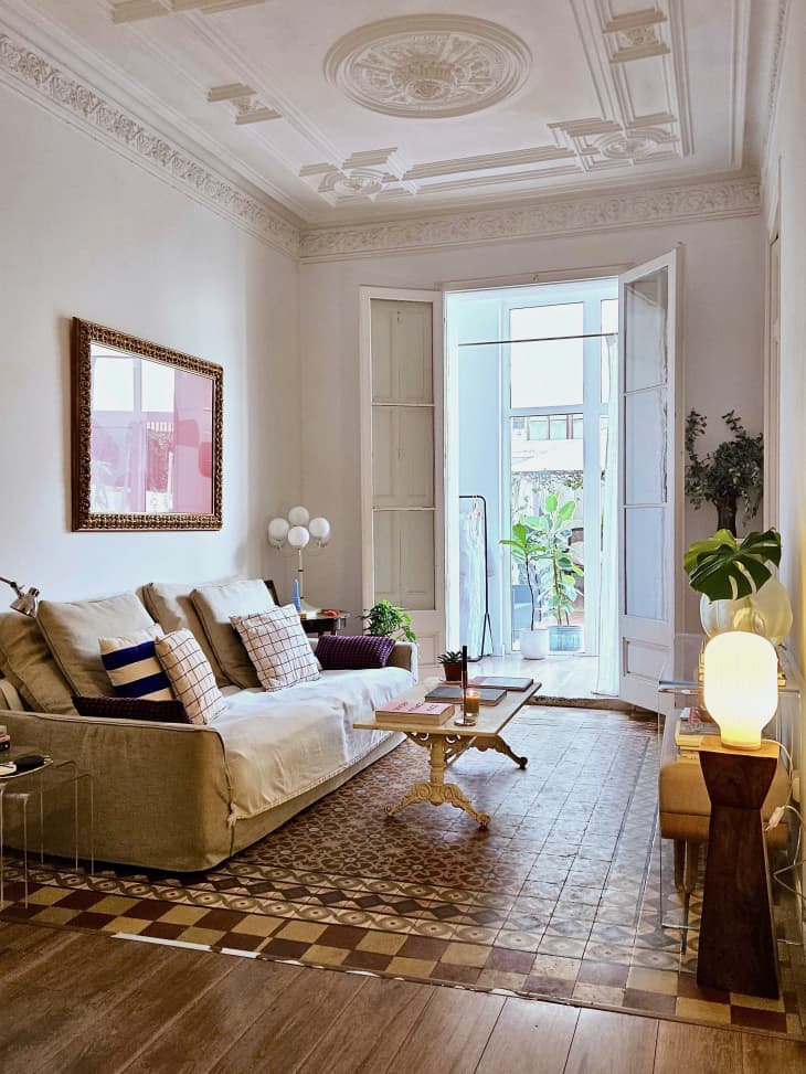 A living room with sofa and coffee table on a tile floor.