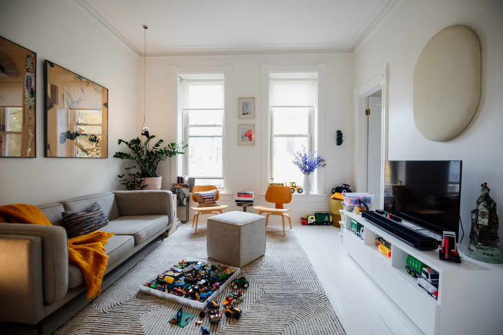 Toys scattered on patterned rug in grey hued living room.