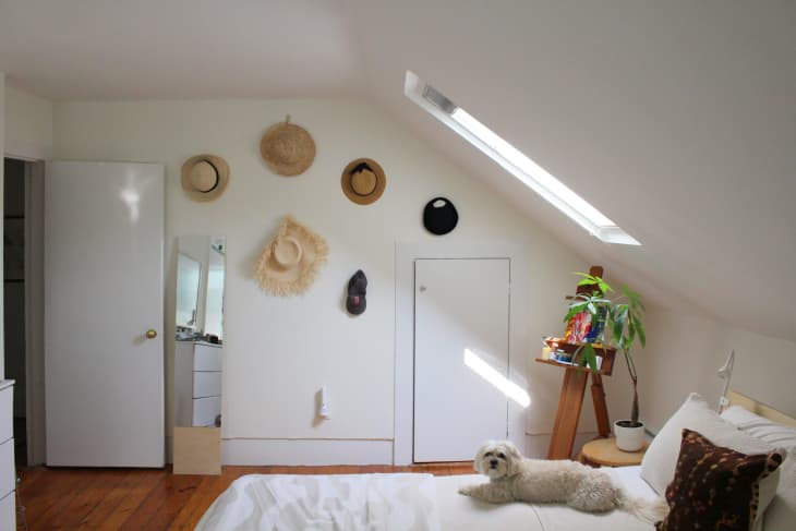Straw hats mounted on wall in light filled bedroom.