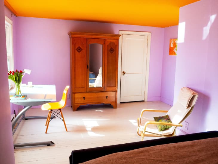 A glass table with an orange table and tan lounge chair in the bedroom.