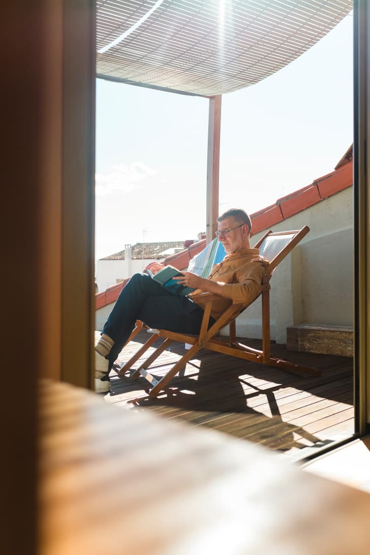 person sitting and reading on their apartment deck