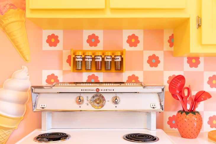 Spice rack lined up behind vintage electric stove in newly renovated kitchen