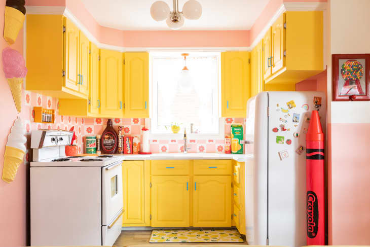 Colorful kitchen with bright yellow painted cabinets and pink walls.