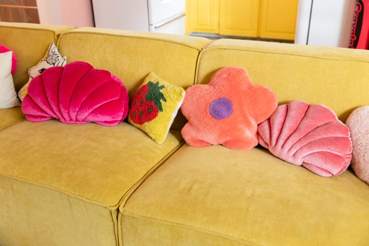 Colorful decorative pillows on yellow sofa.