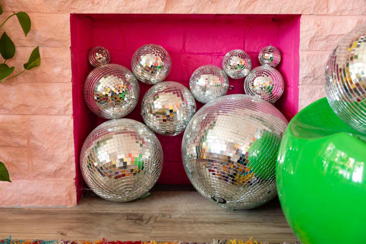 Disco balls filling pink painted fireplace.