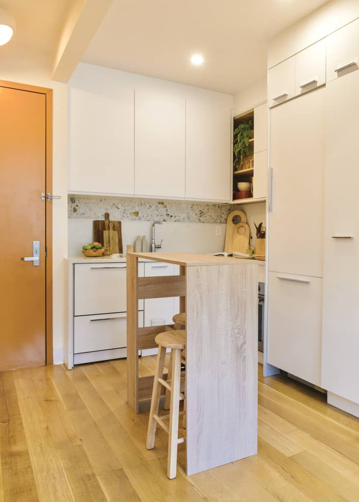 white kitchen with white cabinets, terazzo backsplash, and island with 2 barstools