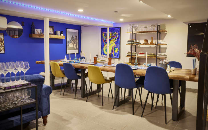 Blue and yellow dining chairs at long wooden dining table in NYC apartment.