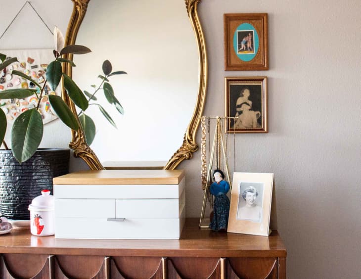 A mirror and other decorative items on a modern dresser.