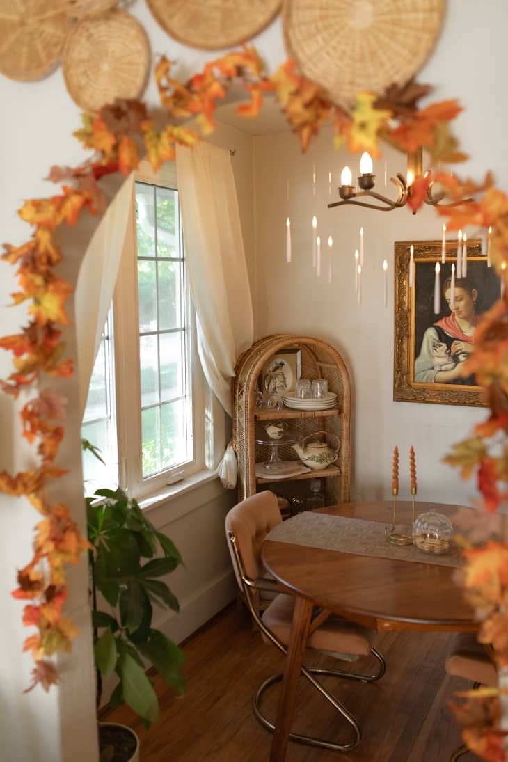 view into white dining room from arched doorway decorated by fall leaves