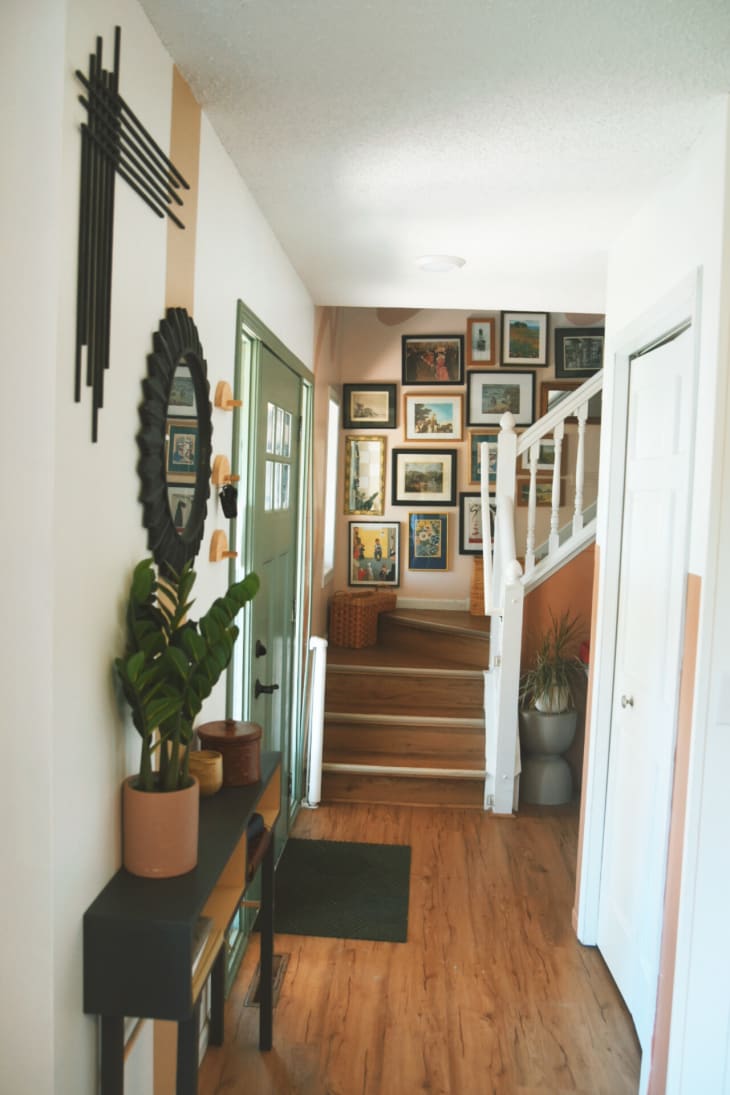 white hallway with green front door and stairwell with gallery wall