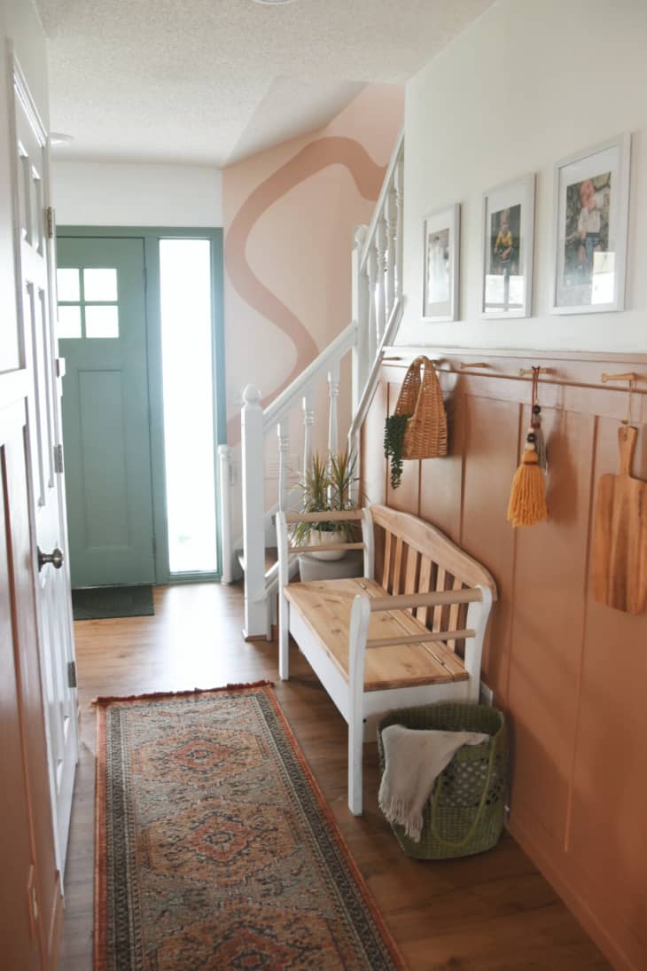 white and terracotta hallway with wood and white bench and view of blush stairway area