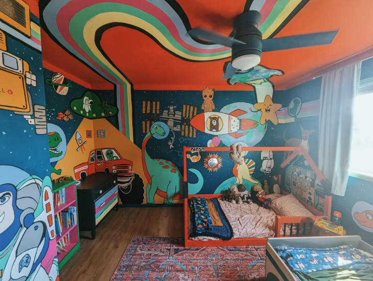 kids room with colorful space and dinosaur themed painted walls and ceiling