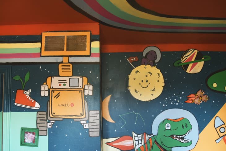 kids room with colorful space and dinosaur themed painted walls and ceiling