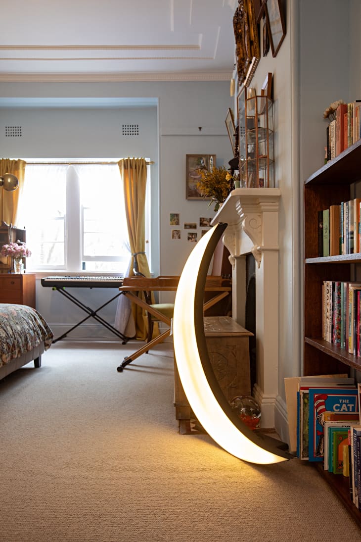 A light up moon decoration sits next to a bookshelf in a bedroom.