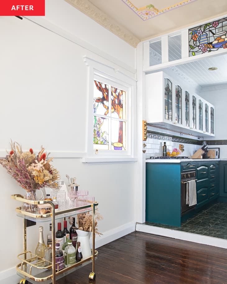 view into white kitchen after renovation with blue cabinets and stained glass accents