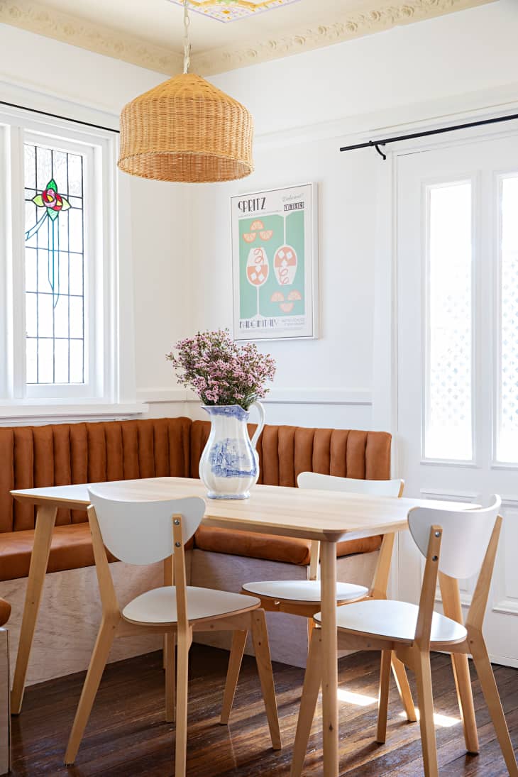 A breakfast nook surrounds a dining table with three chairs in a white kitchen with decorative wall dressings.