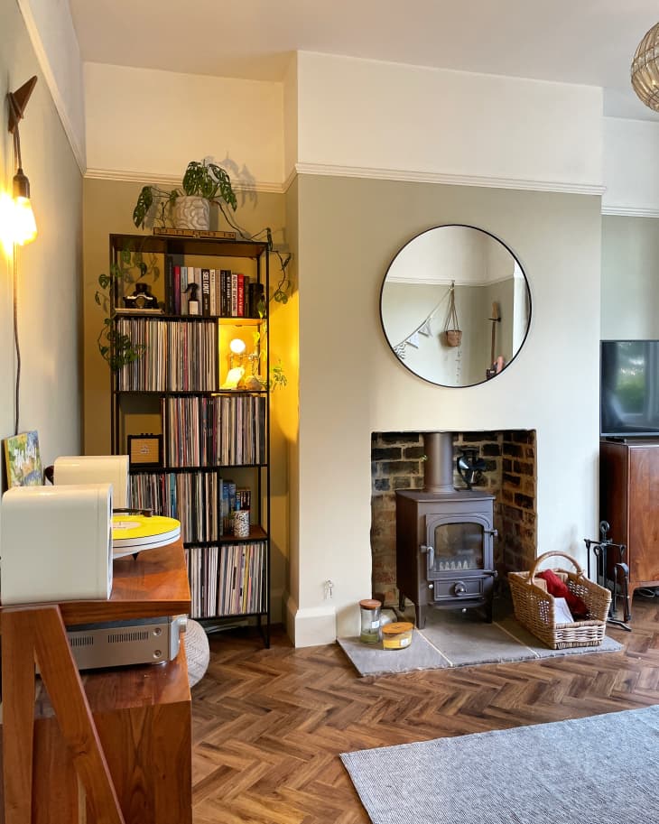herringbone wood floor, fireplace with exposed brick, record player and large white molding along ceiling