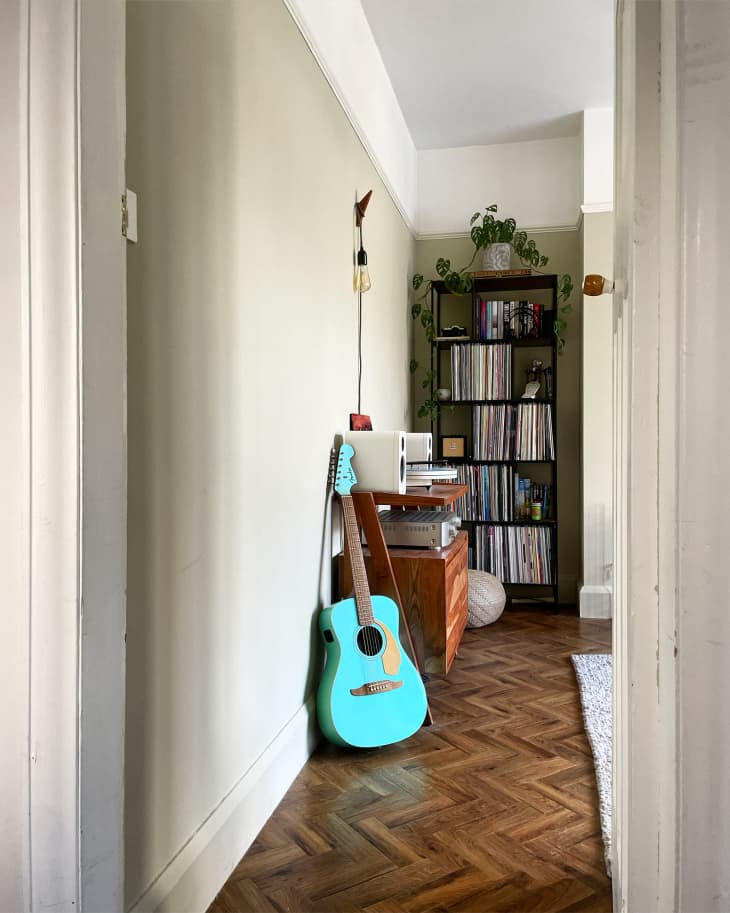 herringbone wood floor, bright blue guitar, vinyl records on tall book shelf
