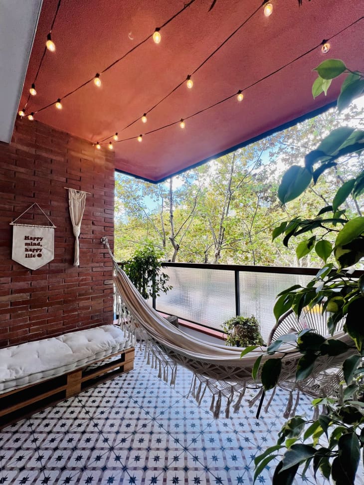 hammock on covered balcony with diamond patterned tile floor and string lights