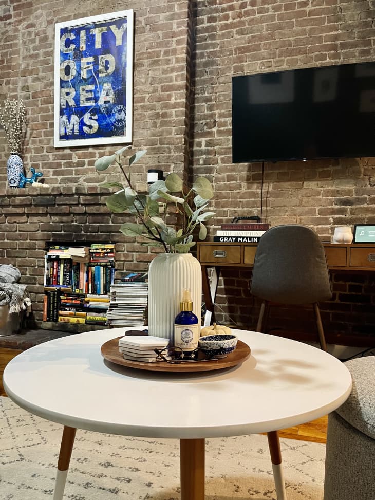Workspace area in living room with exposed brick wall and fireplace full of books