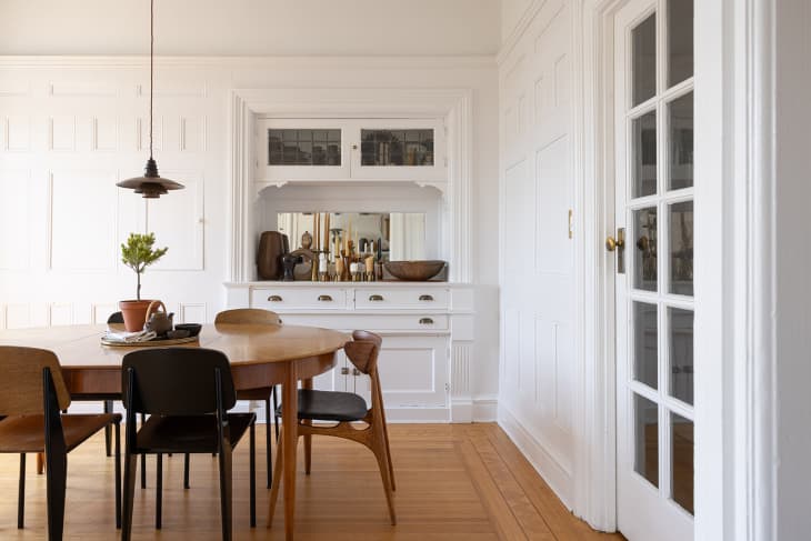 white dining room with built in cabinet and drawers, oval wood dining table and midcentury modern chairs