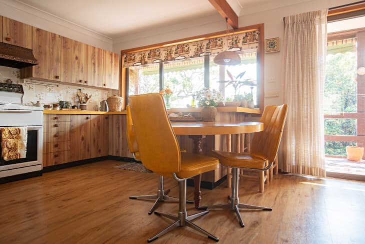 Vintage leather dining chairs surround yellow laminate dining table in vintage inspired kitchen.