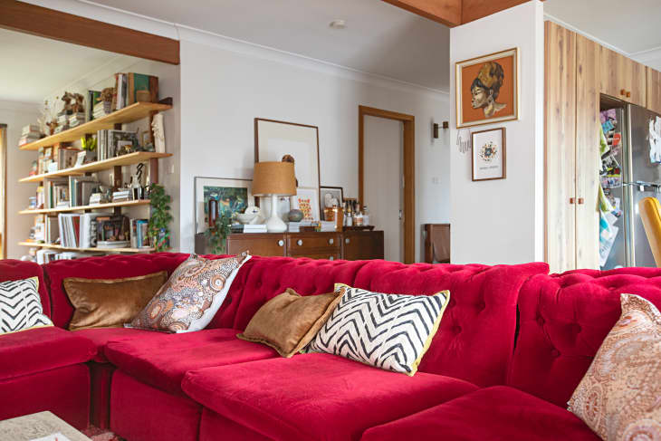 Red velvet sofa topped with decorative pillows in mid century modern home.