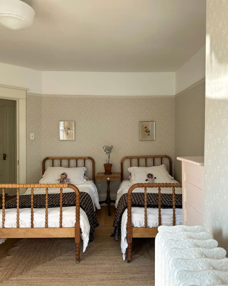 Twin beds side by side in neutral bedroom with beige floral wallpaper.