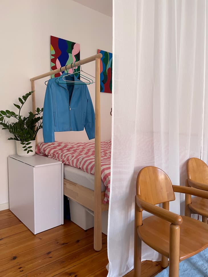 Clothes hanging on wooden bed frame in studio apartment.