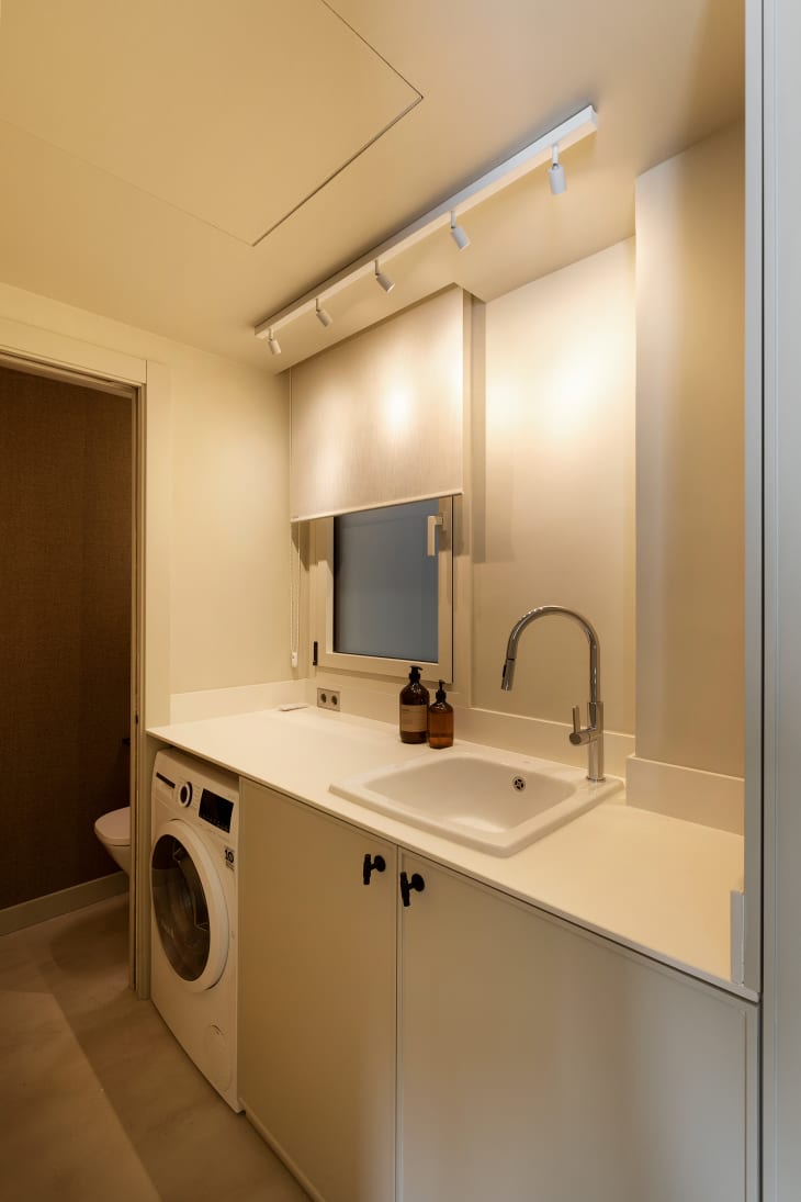 minimal white bathroom with laundry facilities under counter