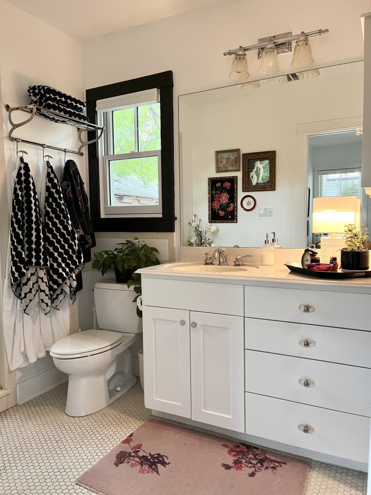 White-tiled bathroom with white cabinets and large mirrors.