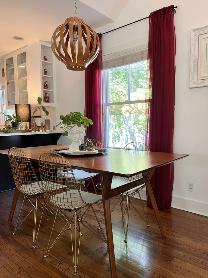 Wooden chandler above wooden dining room table with metal mesh chairs.