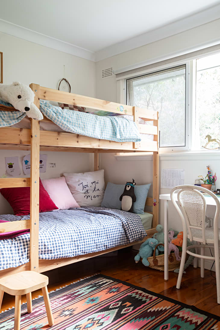 white kids room with wood bunk beds and colorful patterned rug