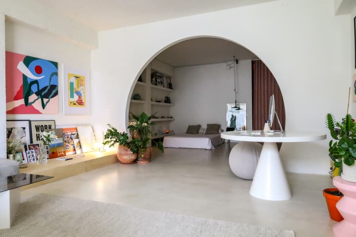 Arch looking into bedroom in art and plant filled apartment.