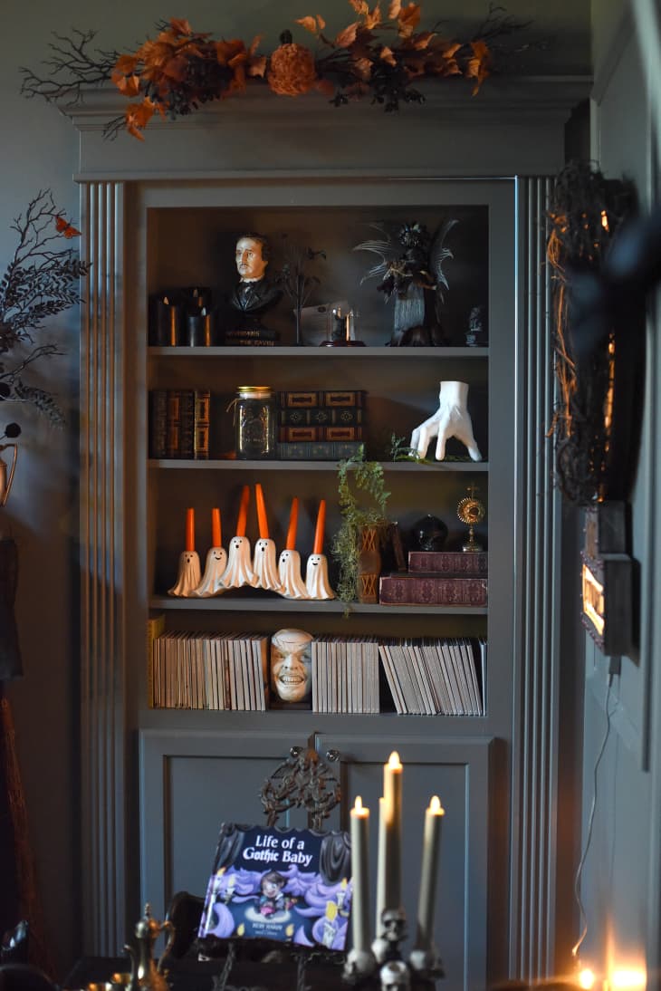 Grey painted bookshelf filled with halloween decor.