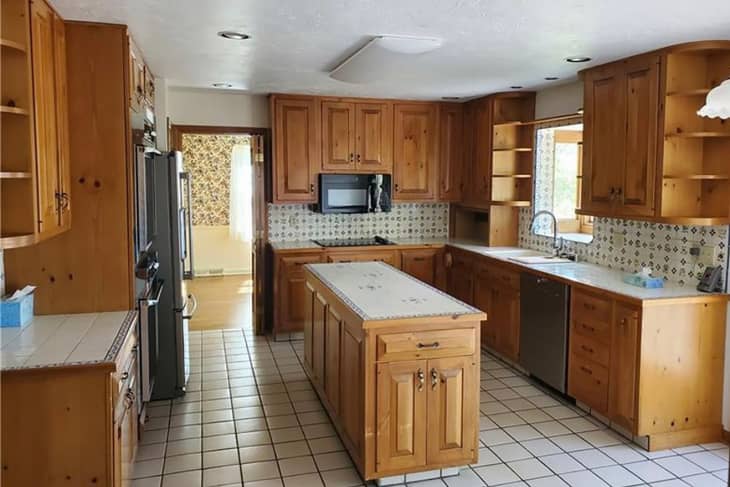 White tile in kitchen with wooden cabinets before renovation.