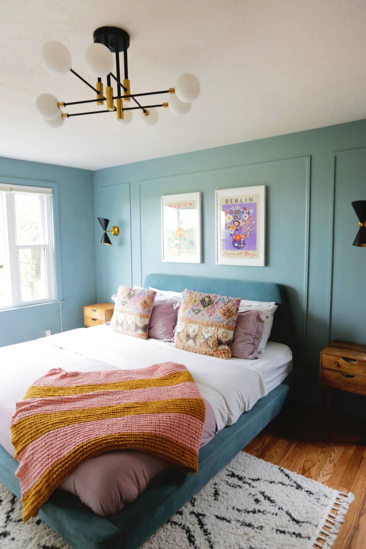 Green painted bedroom with neatly made bed.