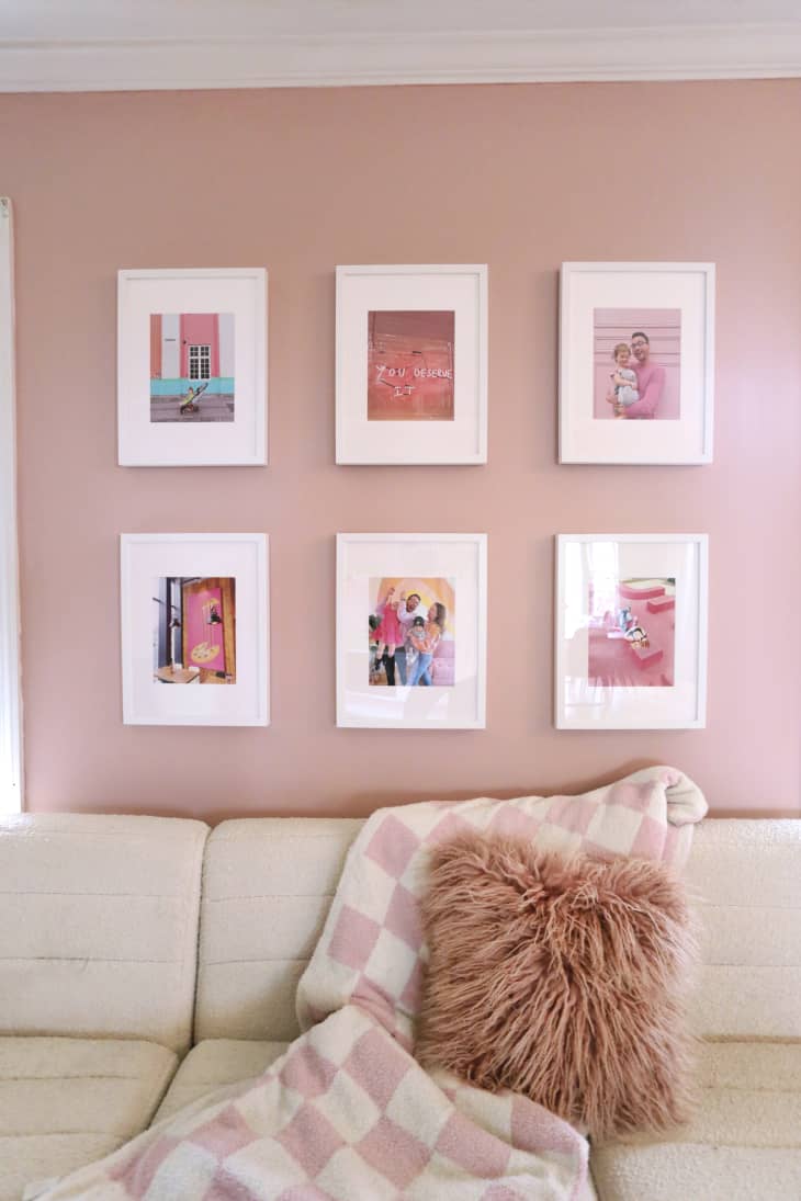 Colorful portrait gallery behind sofa in pink living room.