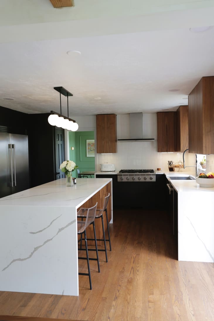 Linear pendant over white waterfall kitchen island.
