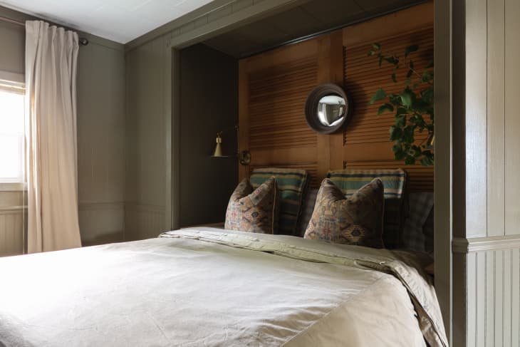 The large bed is against a wooden accent wall.