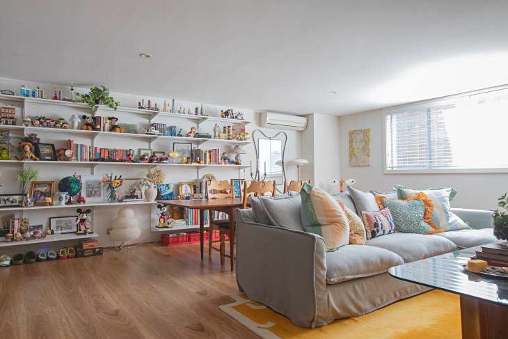 white living room with gray sofa and a full wall covered in shelves for books and art objects