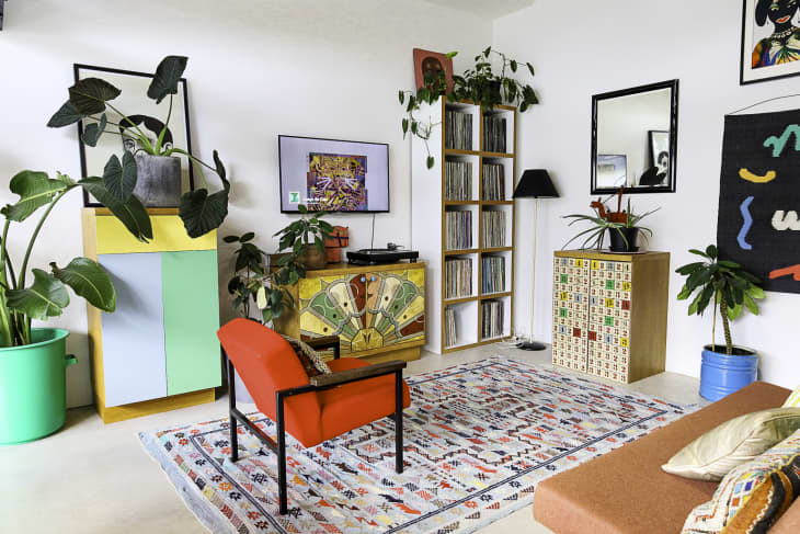 A colorful living room with colored cabinets, and a lounge chair.