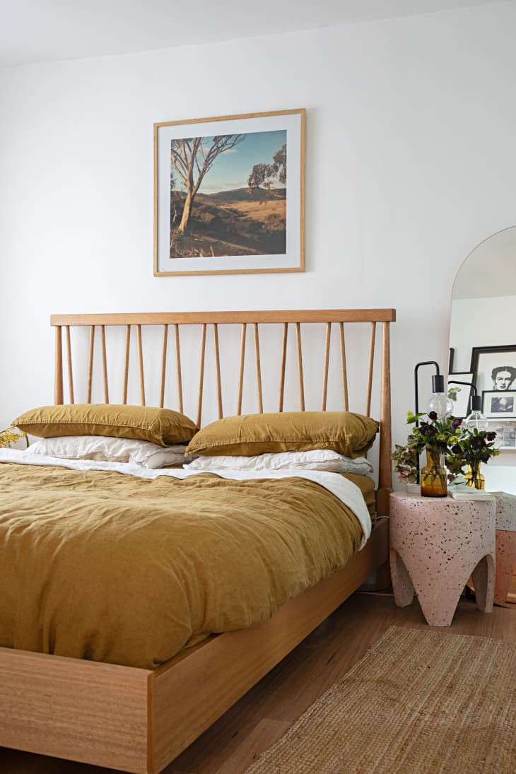 Landscape photo mounted above wooden bed frame.