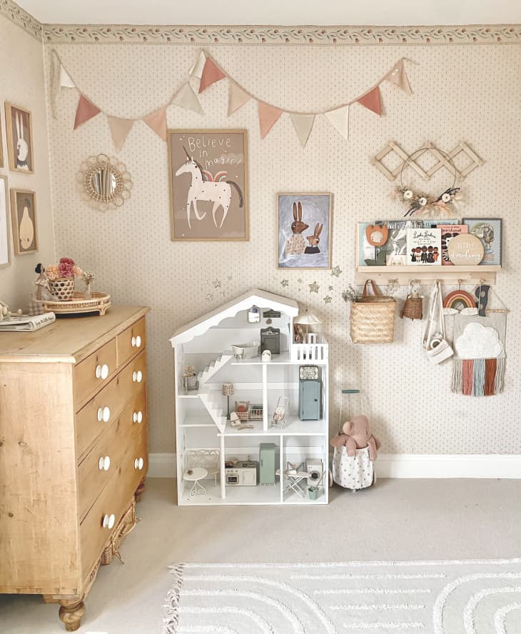Peach kids' room with wood dresser, white dollhouse, and  wall art